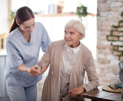Caregiver assisting elderly woman with mobility and daily activities