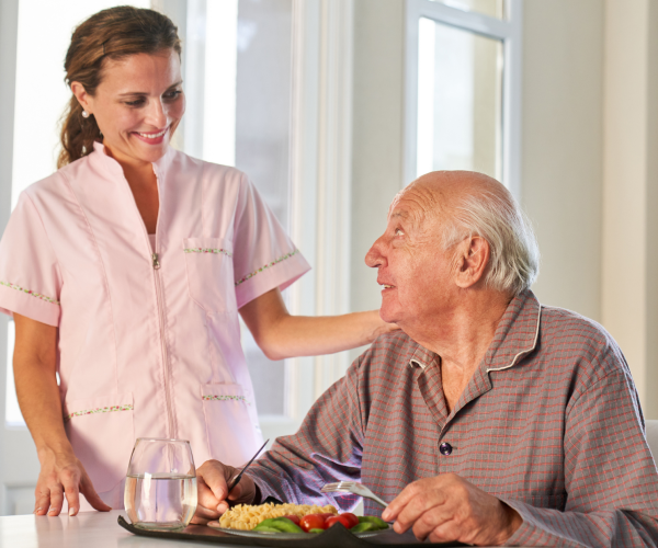 Caregiver providing meal assistance to elderly resident